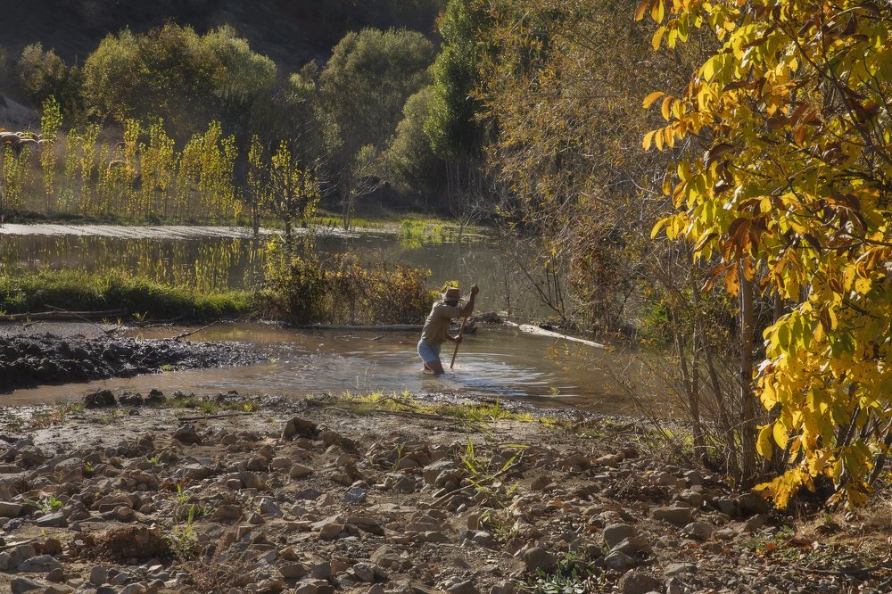 Beautiful autumn season and a man dredging the river