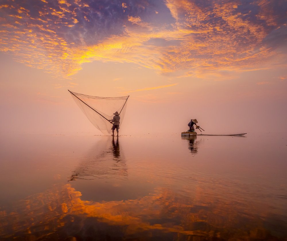 Sunrise at Quang Lang beach and people pulling nets on the sea