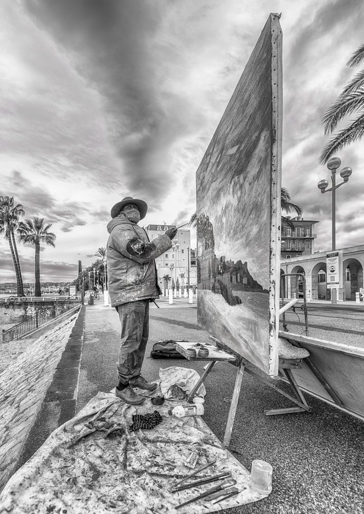 The artist is painting on the street