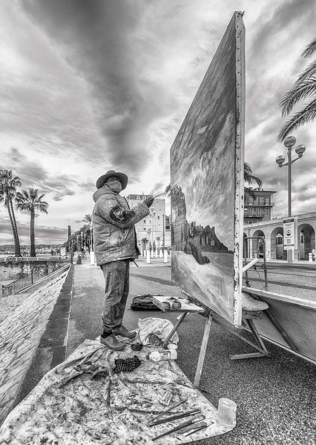 The artist is painting on the street