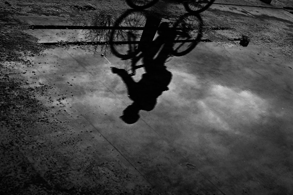 Black and white shadow of a cycler in a water puddle