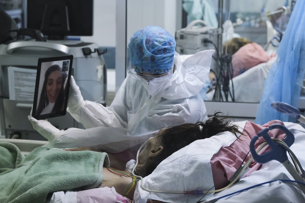 A member of the medical staff holds a tablet in front of a COVID-19 coronavirus patient during a video call with relatives