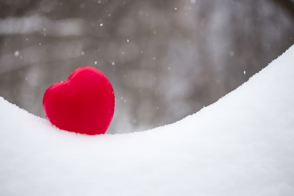 Red heart on white snow