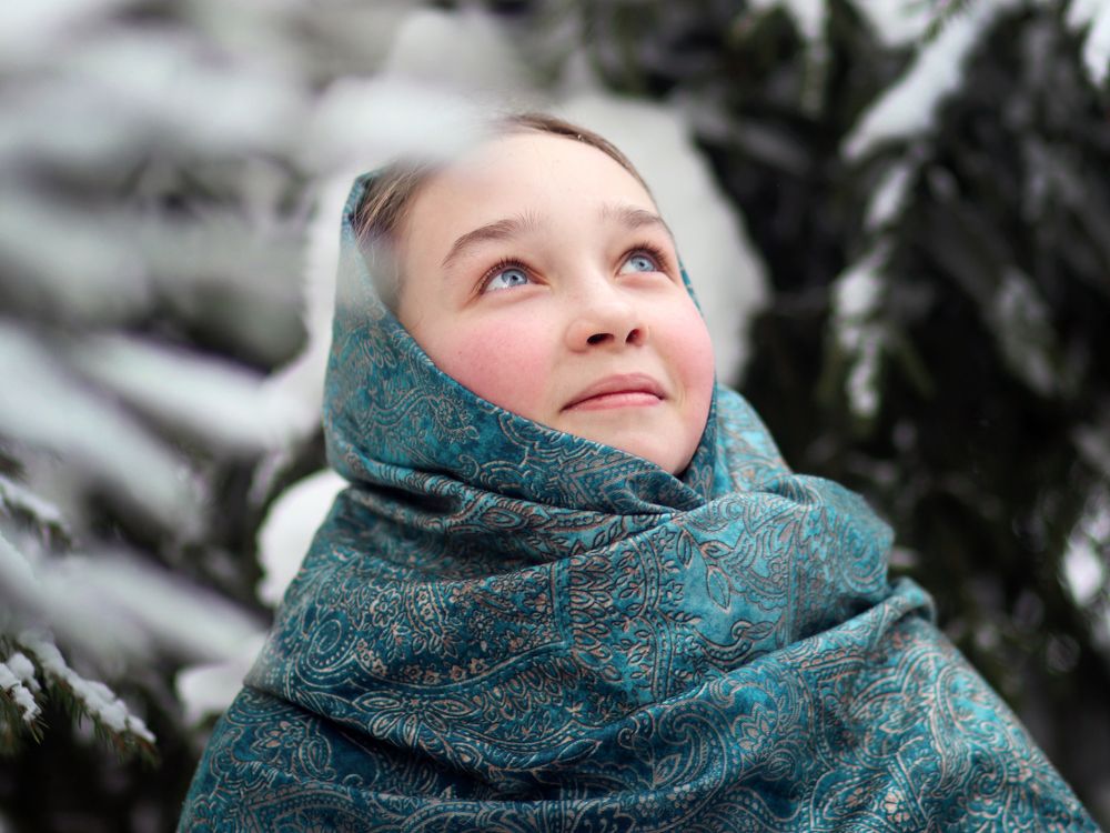 Girl in a dove headscarf look up at the snow