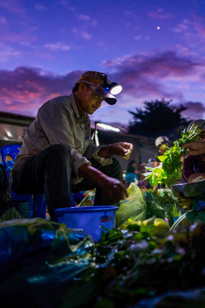 A man selling vegetables at Vi Thanh wholesale market early in the morning.