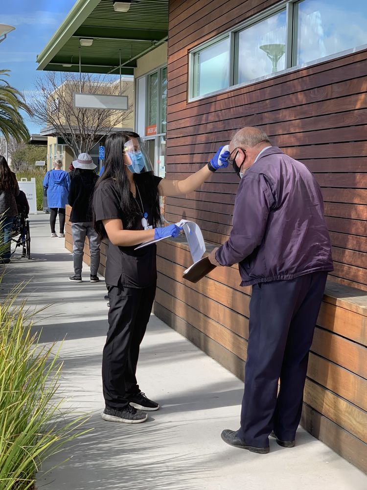 Nurse checks a senior man  temperature.