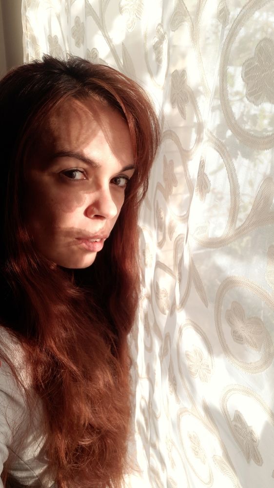 The girl is standing near the window.