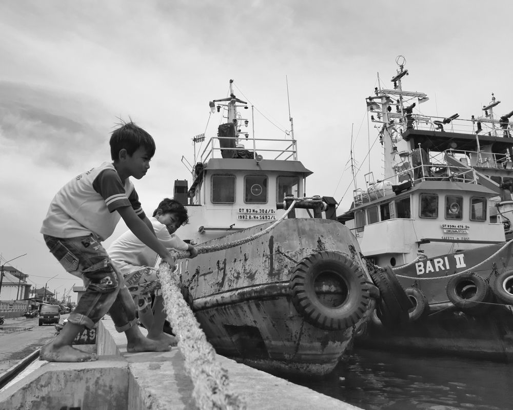 Two children trying to tow a ship