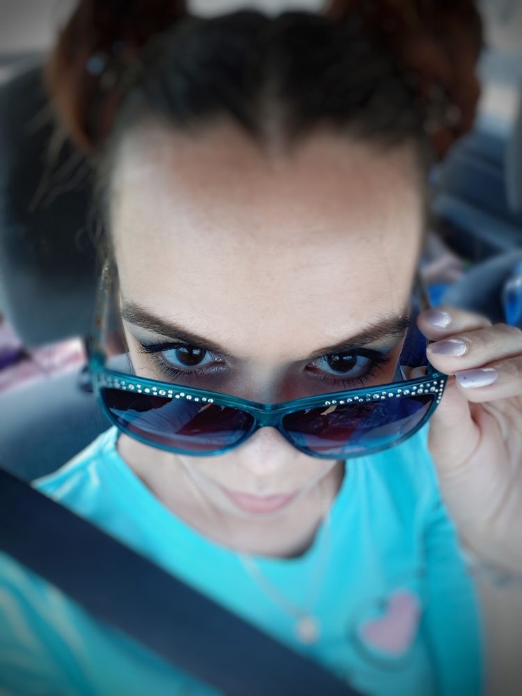 Girl eyes looking over sunglasses.