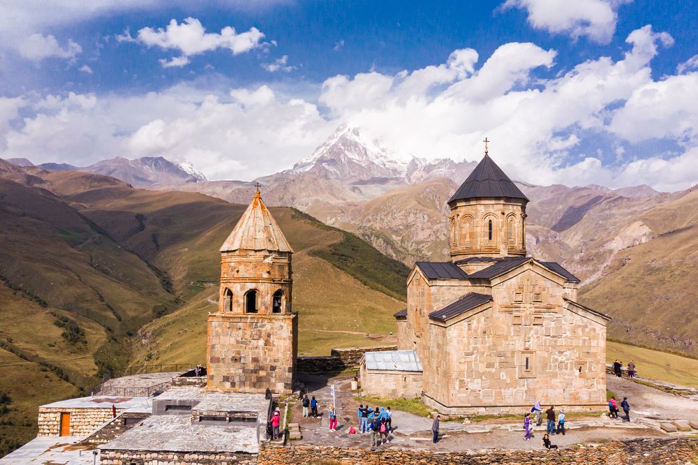 Вид с птичьего полета на древнюю церковь Троицы Живоначальной на фоне горы Казбеги. Грузия, Гергетти, Степанцминда.