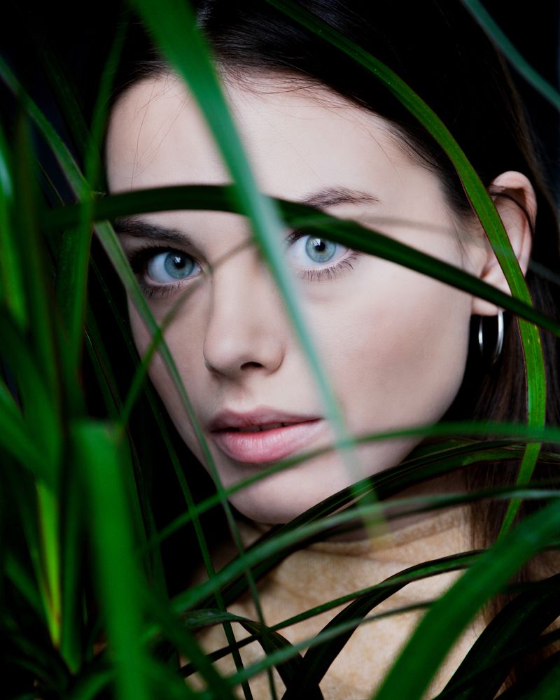 Девушка, смотрящая сквозь листья растения
