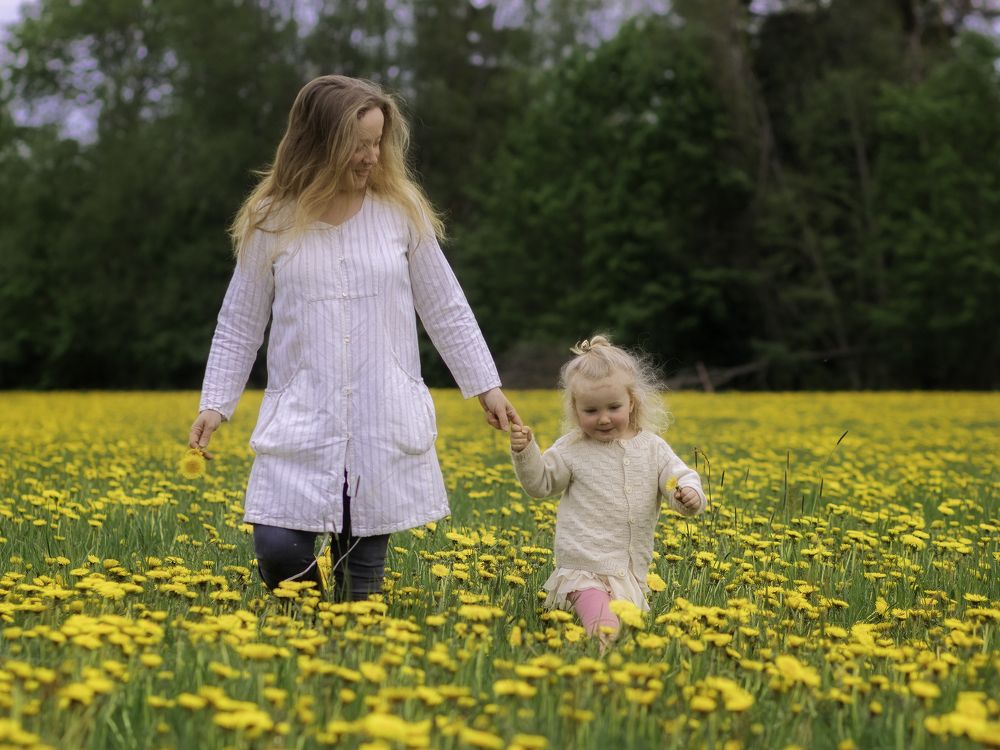 Mom and daughter on dandelions field