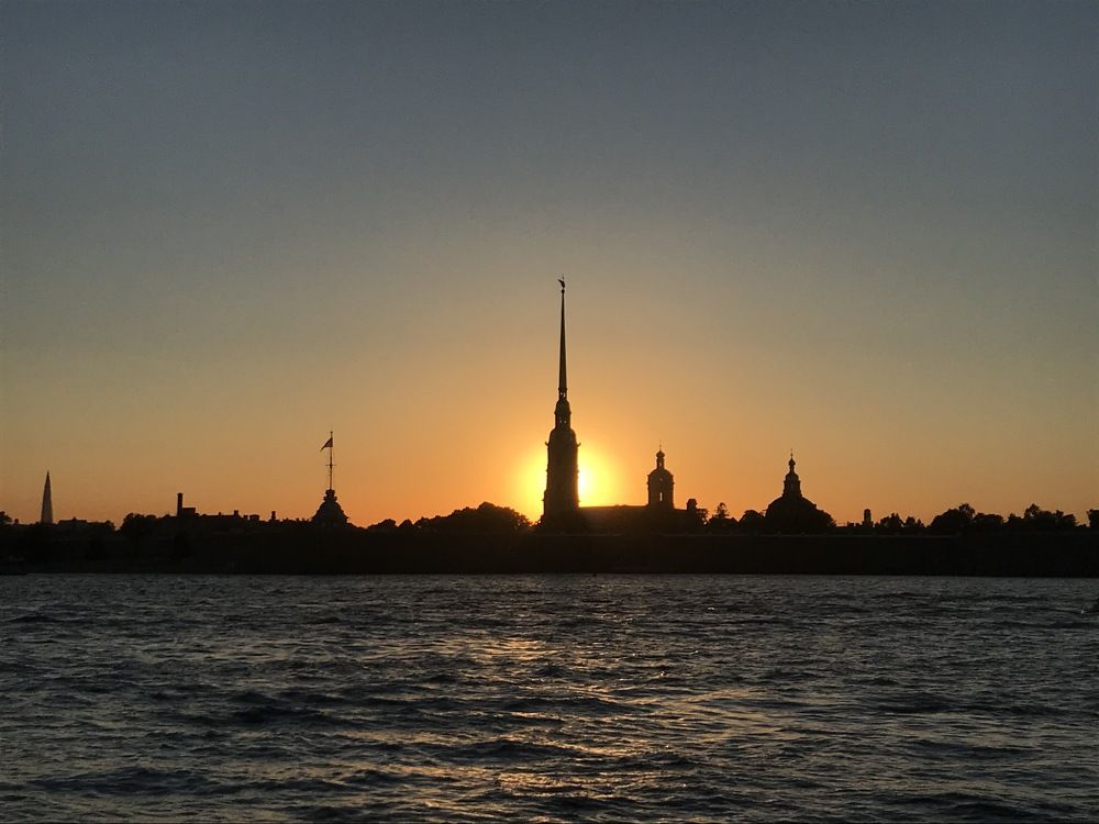 Линия Петропавловской крепости в ореоле уходящего за горизонт солнца