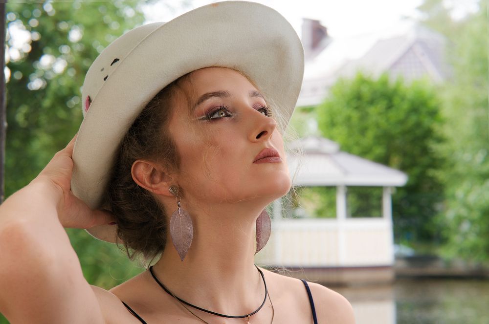 Девушка в шляпе на фоне беседки