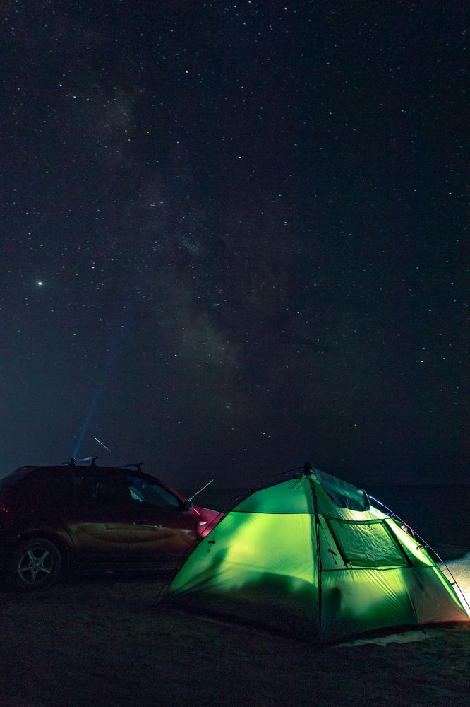Green tent and car under milky way