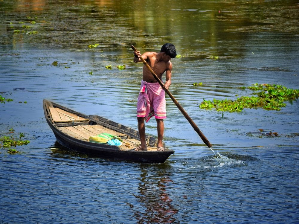 A fisherman is rowing in a river.