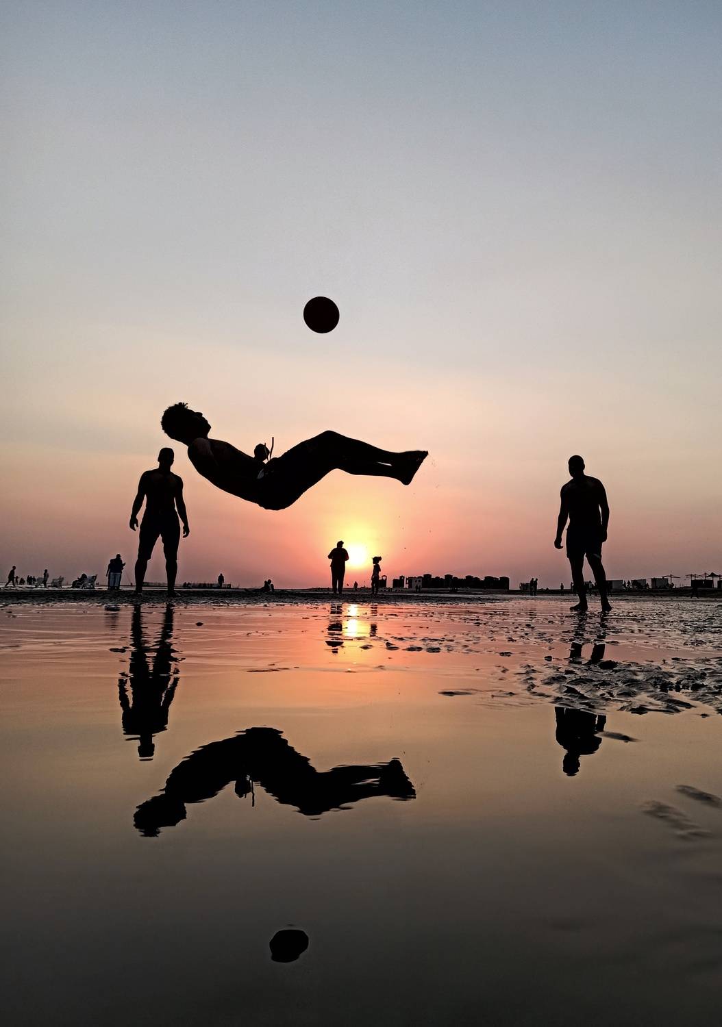 Some friends enjoy playing soccer at the seaside