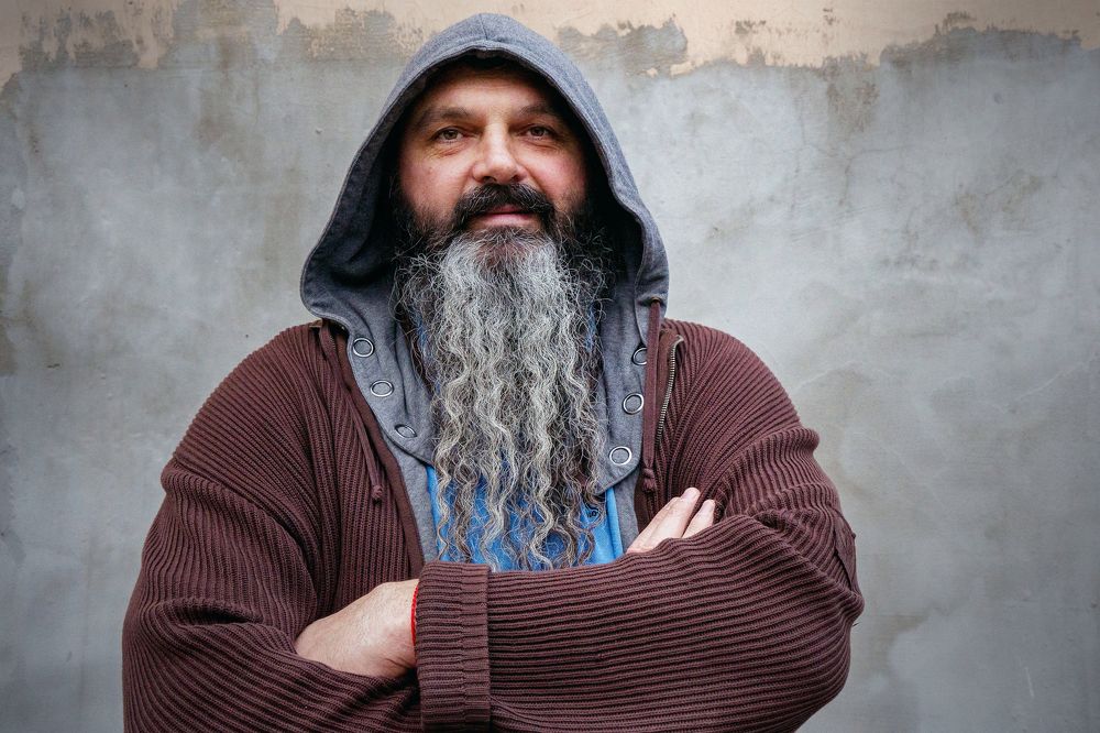 Мужчина с бородой на фоне серой стены