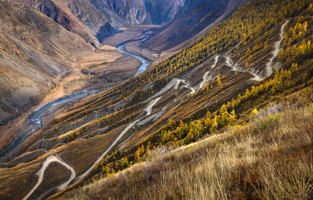 The road is rocky along the mountain slope, descending into the valley of the mountain river.