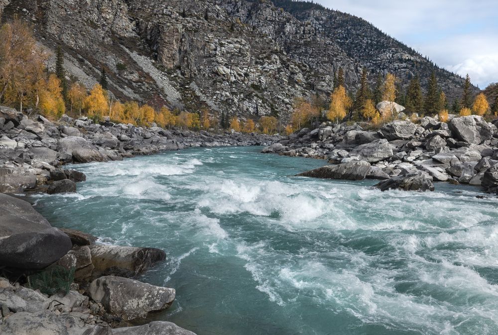 Landscape view of the stormy turquoise river in the valley of the mountains