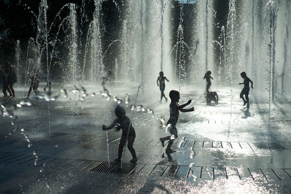 children play with shadows in the fountain