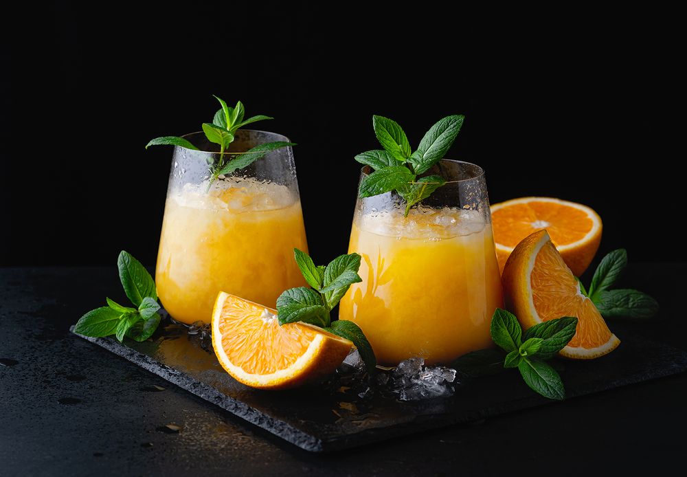 Cold summer orange lemonade with mint and ice in a glass.