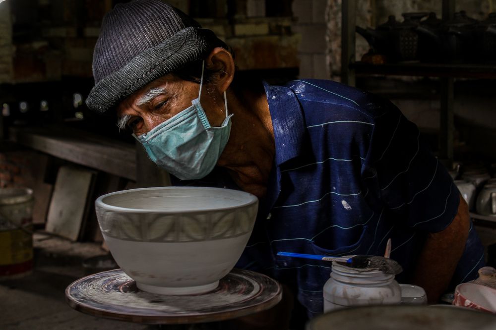 An old man finishes the job of making bowls