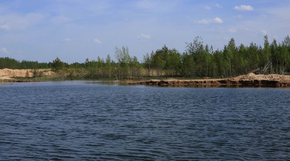 Lake in a sand pit in spring next to young trees