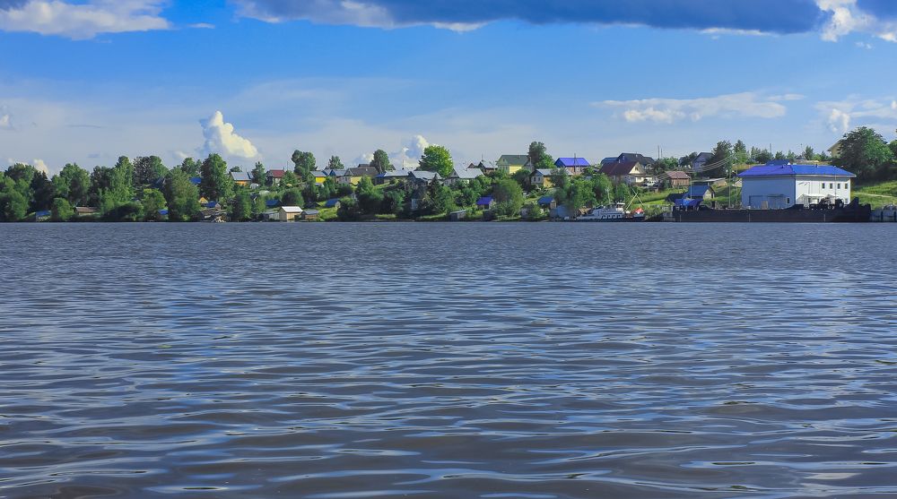 The coastal village of Ivanov Bor from the side of the Sheksna River on a July day