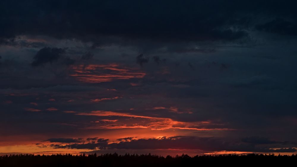 Evening landscape with a setting sun and black clouds