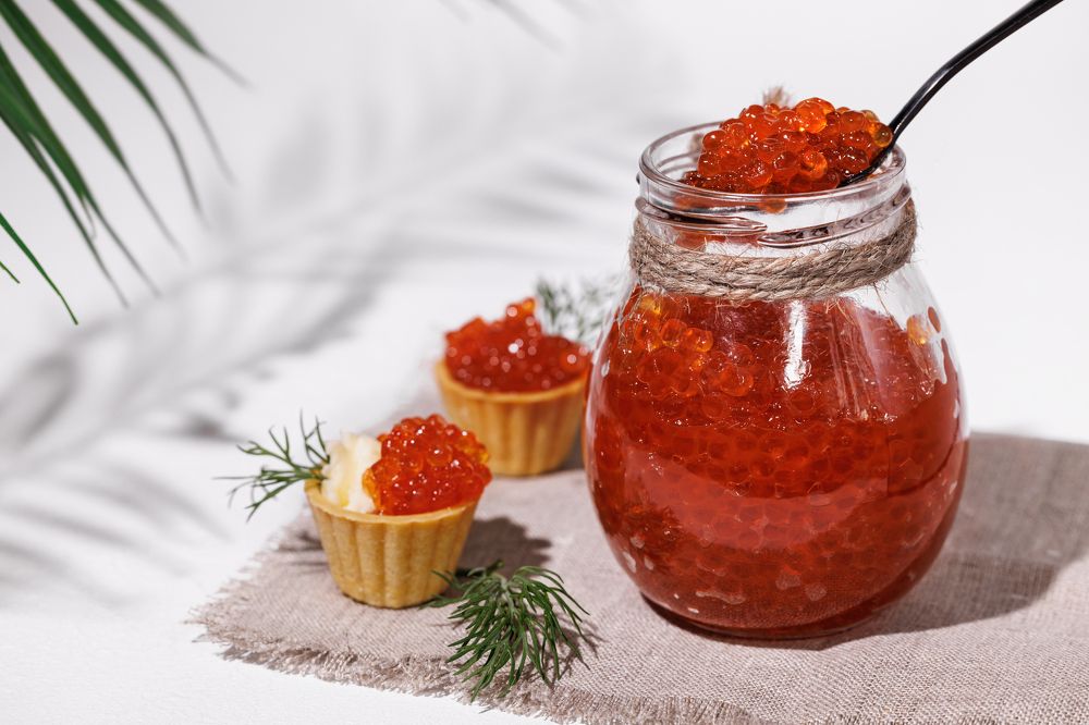 Red caviar in a glass jar with a teaspoon.