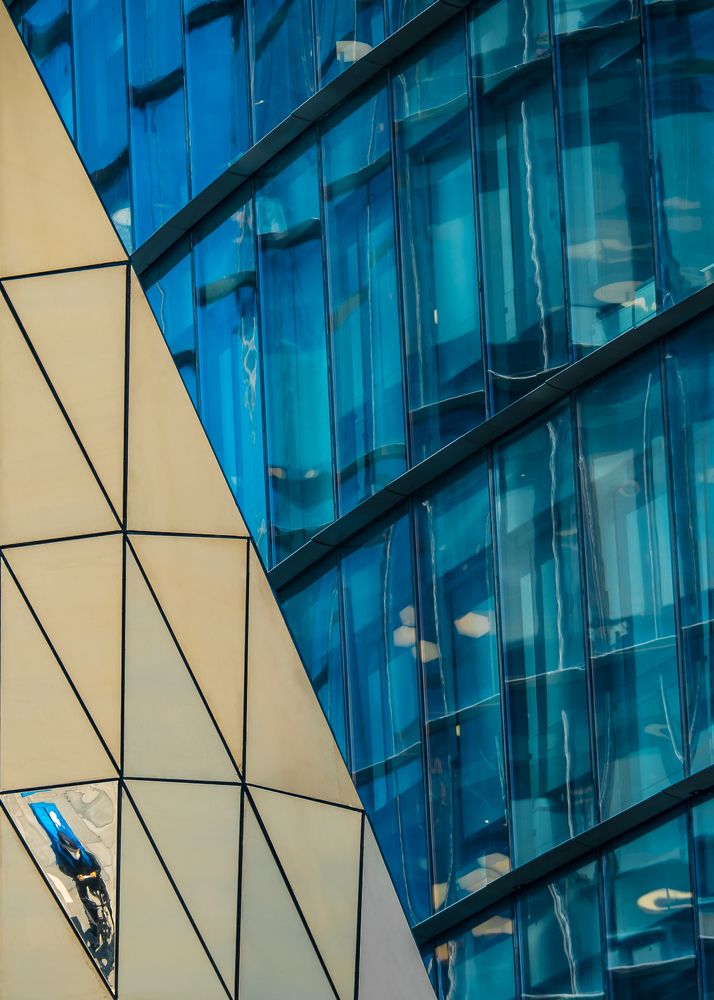 Отражение курьера в козырьке входа в здание Сбер-Сити, Москва, Россия. Август 2021.