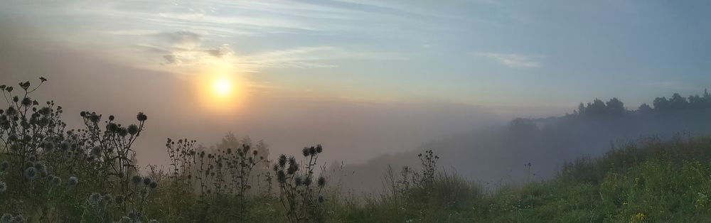 Восход солнца в тумане за рекой.