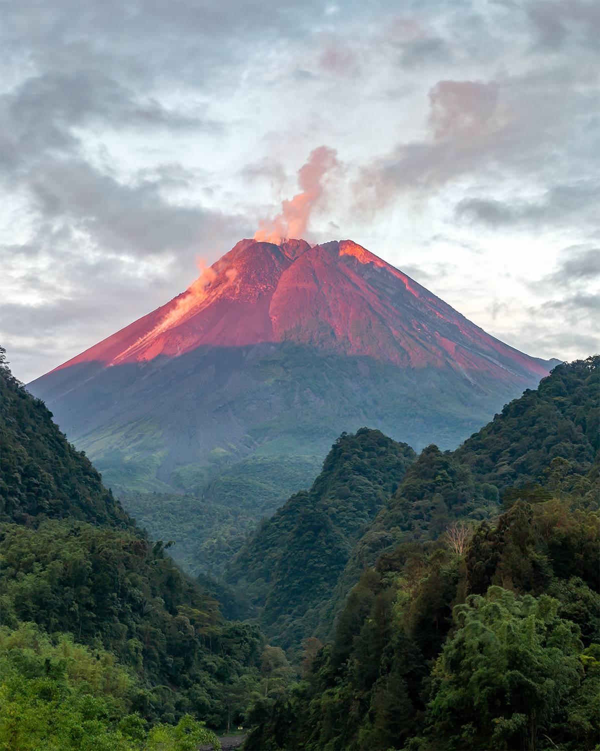 RED ILLUMINATED PEAK OF MT. MERAPI AT SUNSET TIME