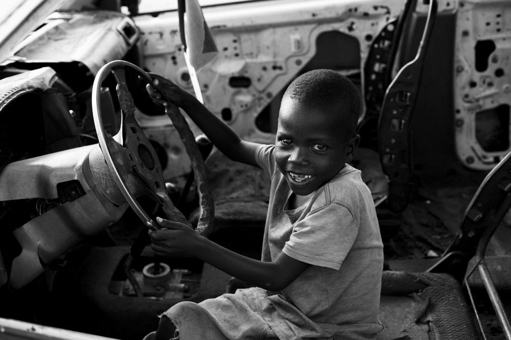 a boy sitting in a rotten car
