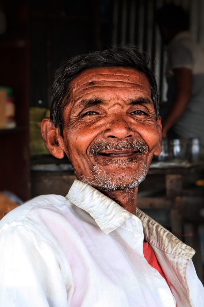A joyful man was sitting on the chair in his shop.