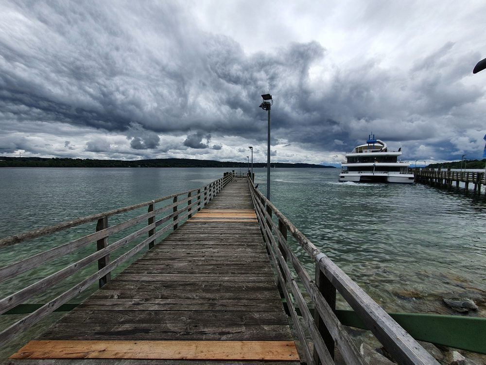 Пустой  серый трап для парохода и грузовые тучи  на озере Штарнберг, Германия