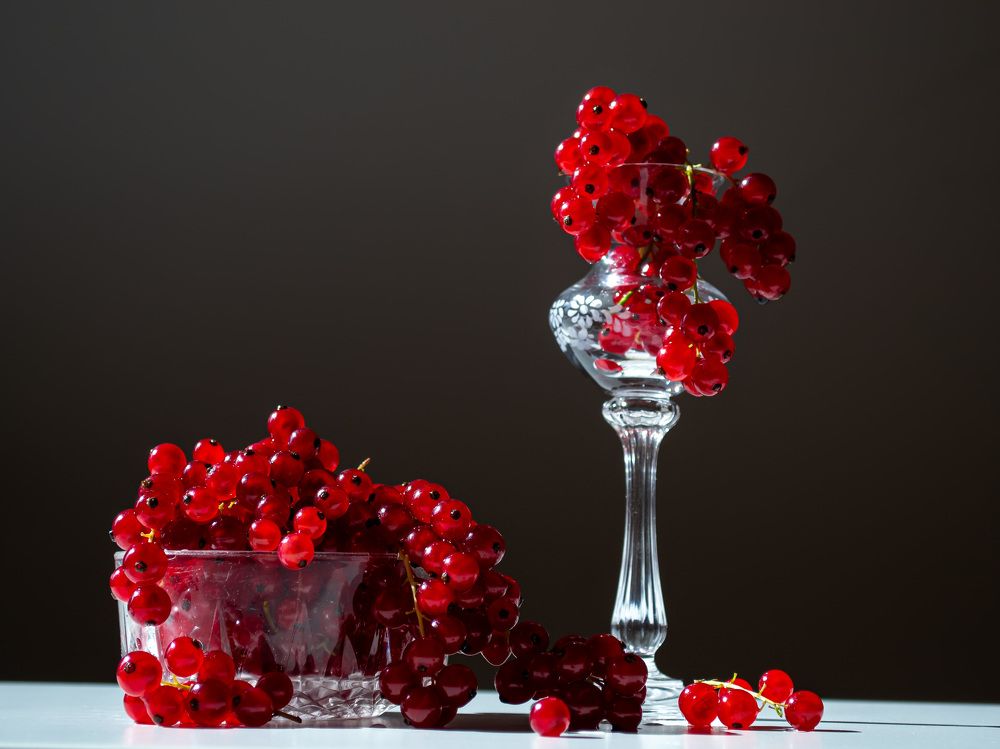 bunches of red currants in a glass bowl on a black background