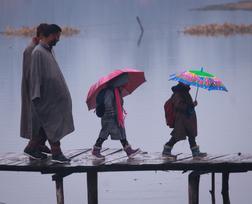 Children's walking on a wooden bridge in Srinagar along with their father