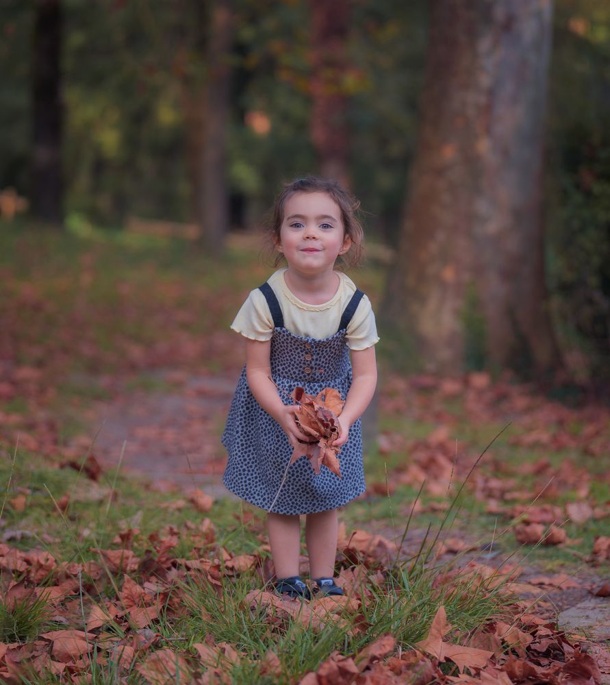 Beautiful girl playing with the fallen leaves