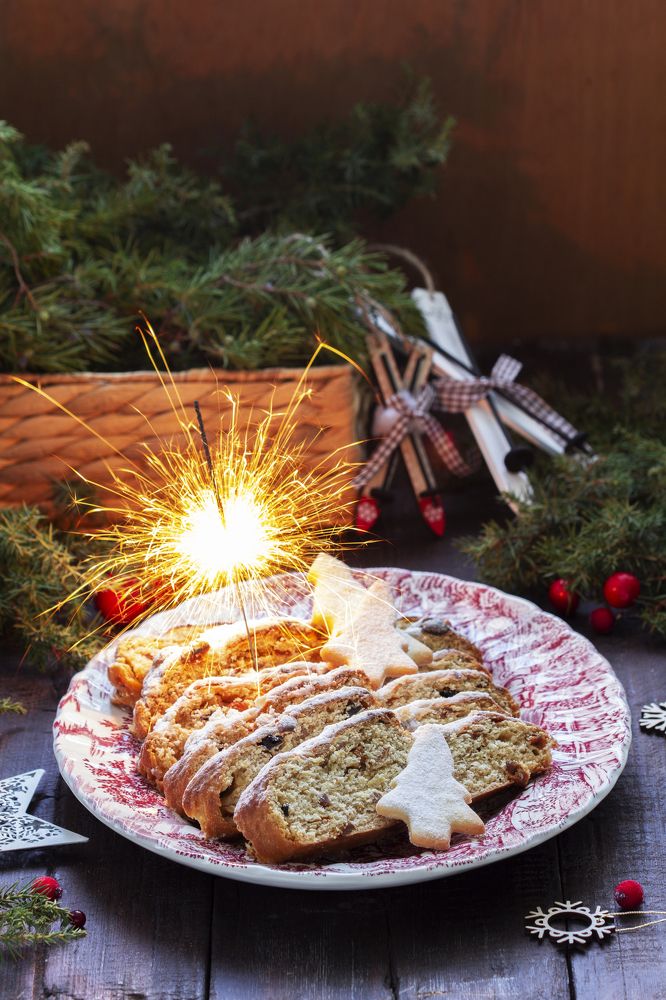 Christmas stollen with dried fruits, nuts and spices, Christmas decorations on a dark wooden background.
