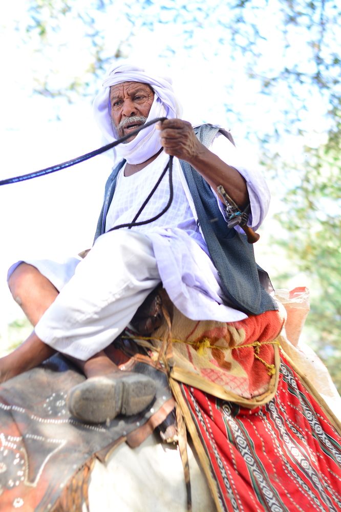 An old Sudanese man riding a camel