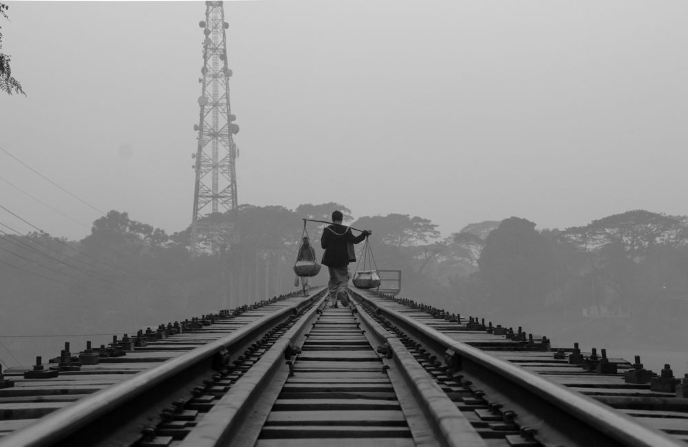 A man walking on the rail bridge, foggy winter morning