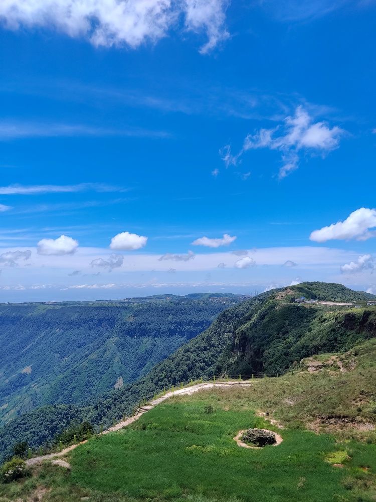 The clear blue skies of Cherrapunji provide a stunning contrast to the lush greenery of the hills below.