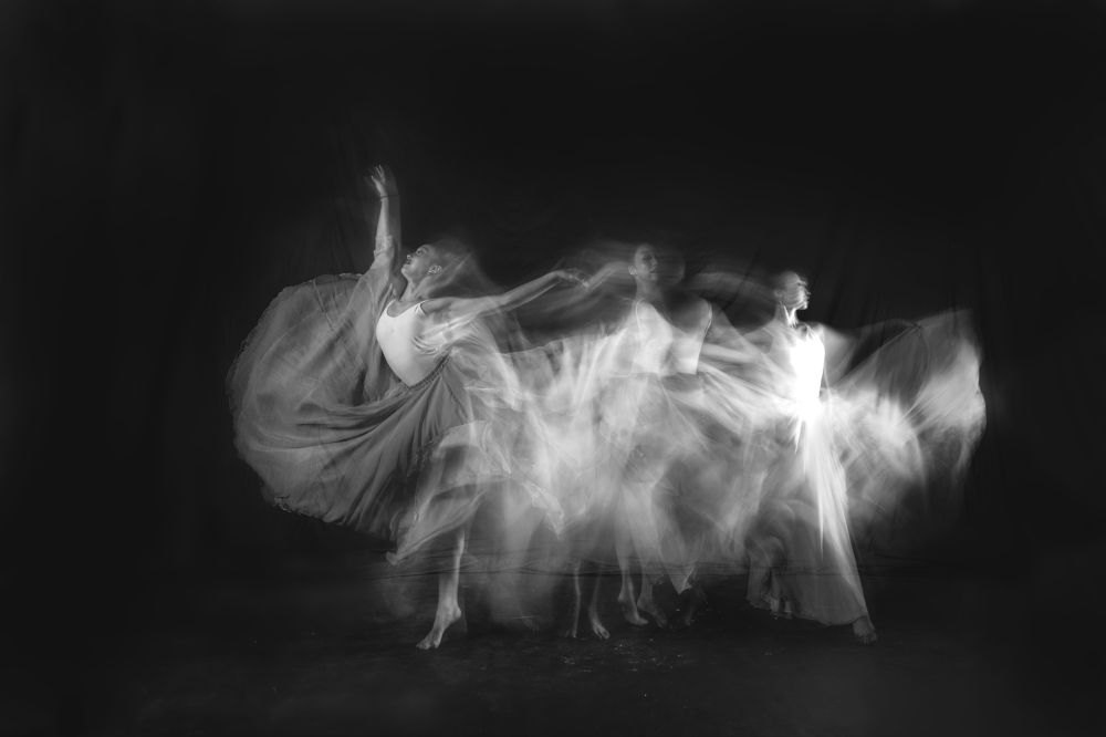 Female ballet dancers dancing against black background