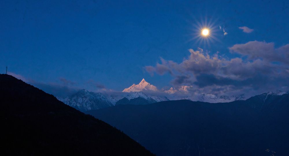 setting moon and snowy mountain