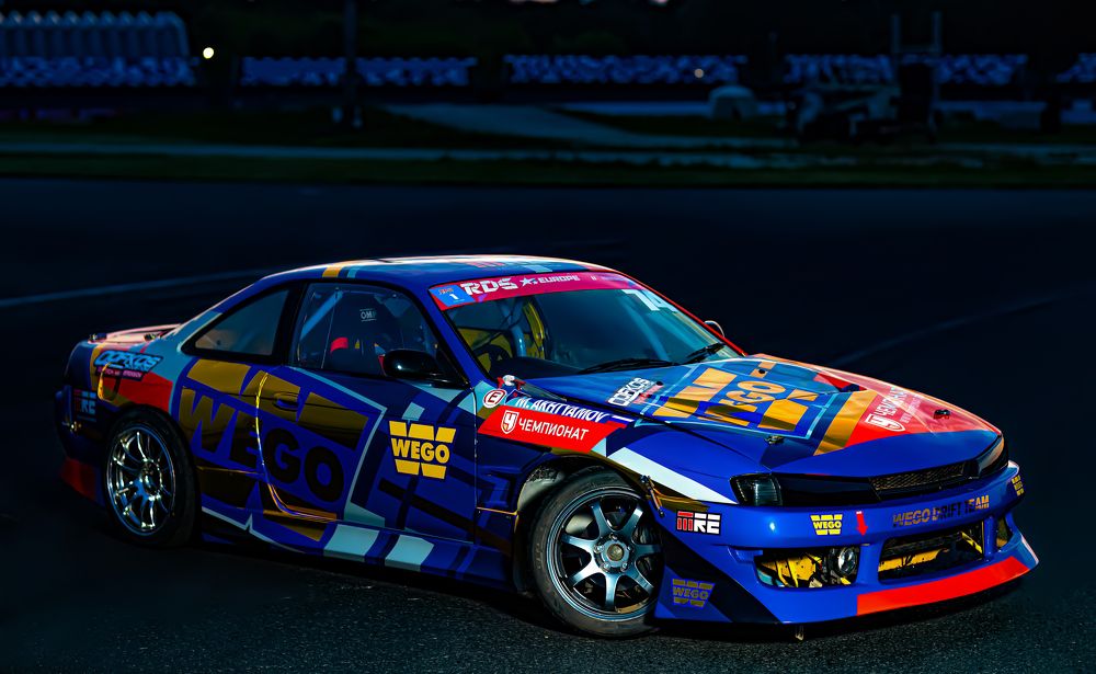 Из темноты.