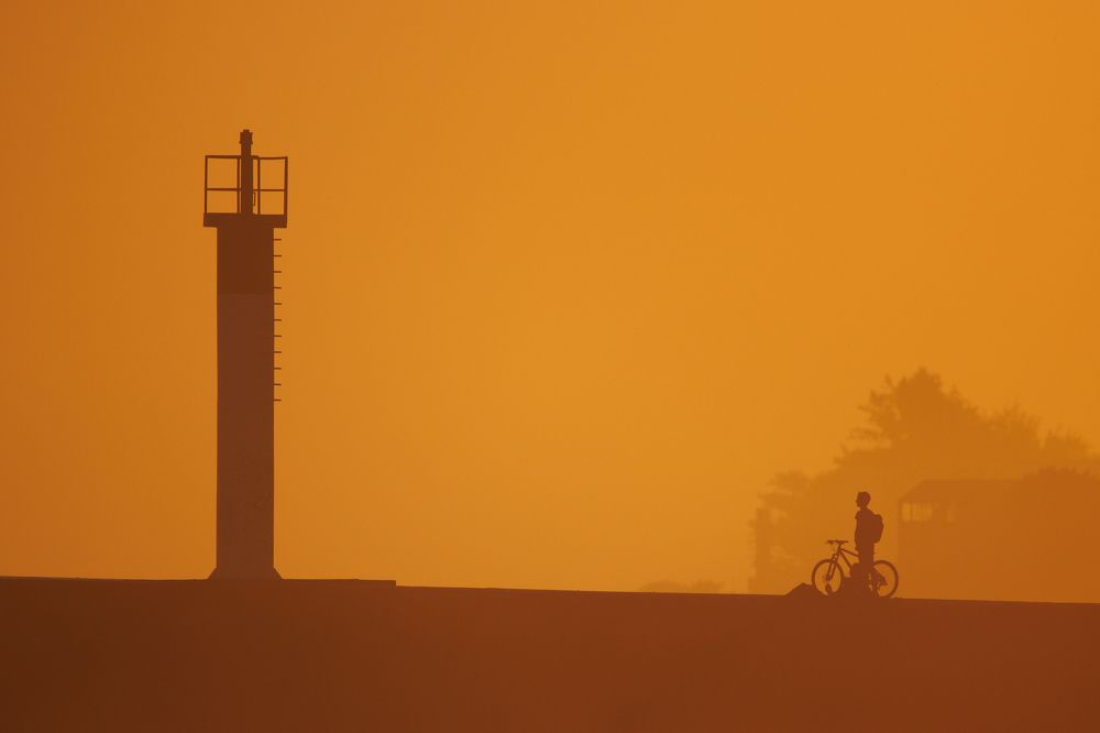 The man on a bicycle facing the lighthouse