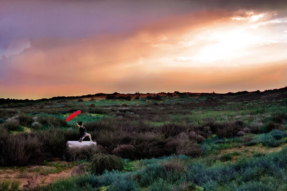 Женщина и зонт на закате в степи.