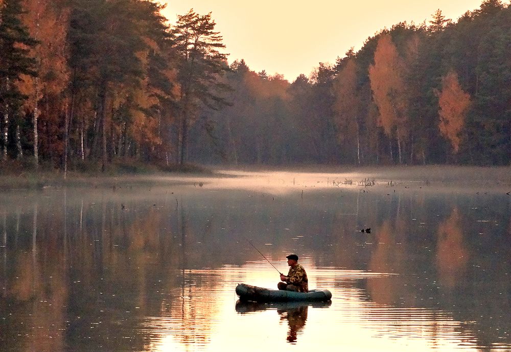 Рыбак в лодке осенью